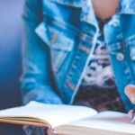 Mujer escribiendo en su diario, un acto de introspección para responder preguntas de autodescubrimiento y conocerse mejor.