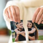 Mujer rompiendo una fotografía de pareja, un símbolo del proceso de dejar ir a alguien que amas tras una ruptura.