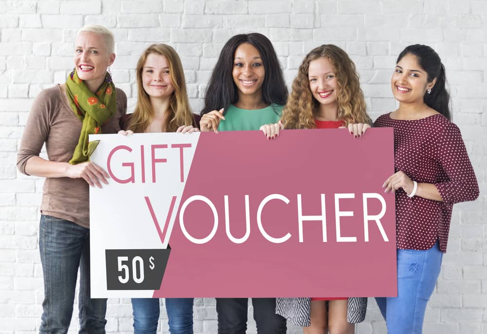 Varias personas mostrando un cartel Gift Voucher gigante