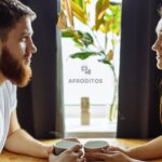 Pareja mirándose con afecto, sentados a una mesa. Consejos para pedir perdón a tu pareja.