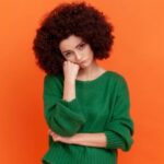 Joven con expresión melancólica preguntándose cuánto tiempo tomará olvidar a su ex.