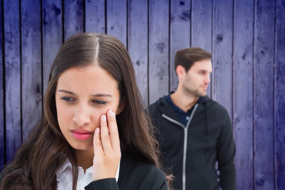 Mujer triste tras ruptura, con su ex desenfocado al fondo. ¿cuánto tiempo se tarda en olvidar a alguien?